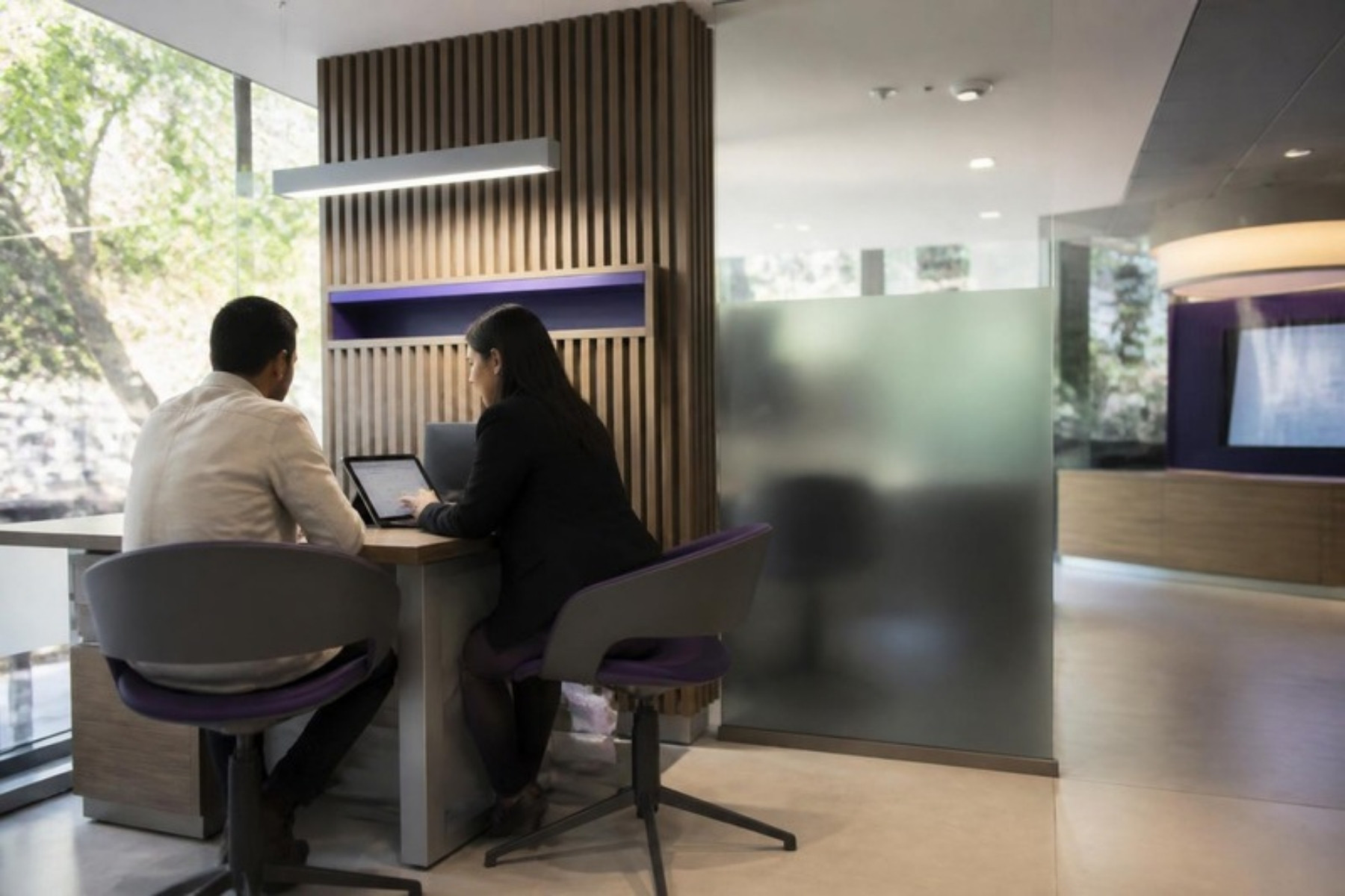 Sucursal bancaria moderna con un ejecutivo atendiendo a un cliente